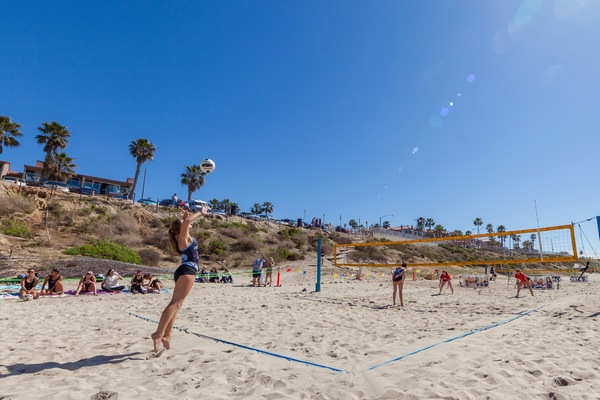 Picture of volleyball player at the beach in Carlsbad with the cliffs in the background.