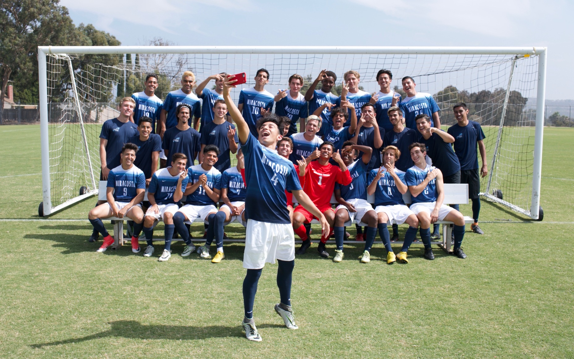 Men's Soccer team picture with Bryan Sahagun in front taking selfie with team behind him.
