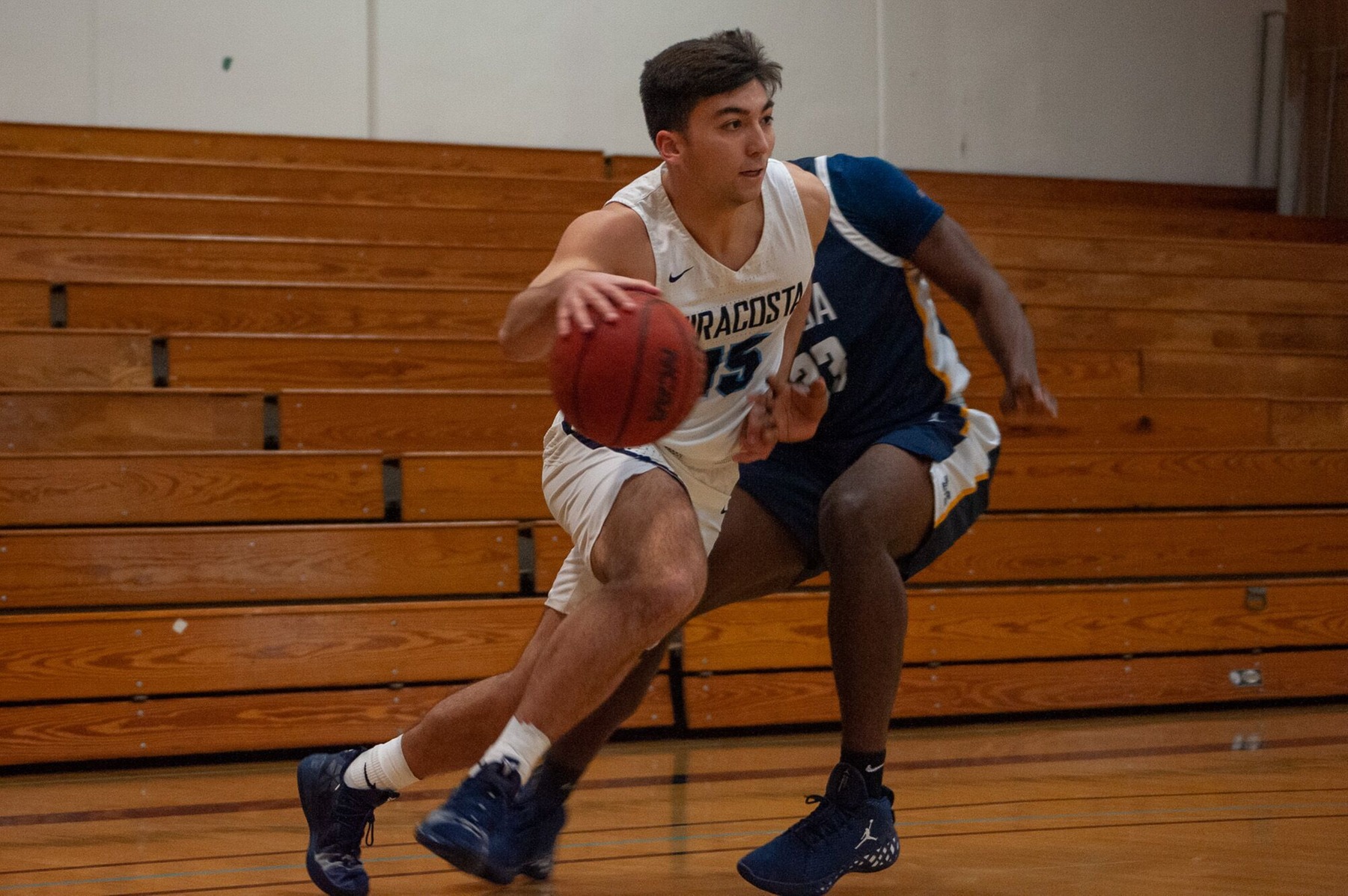 Men's basketball player dribbles towards the basket in a game.