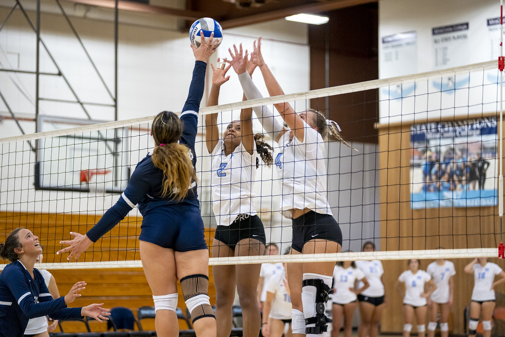 MiraCosta volleyball players jump to block a hit by the opponents.